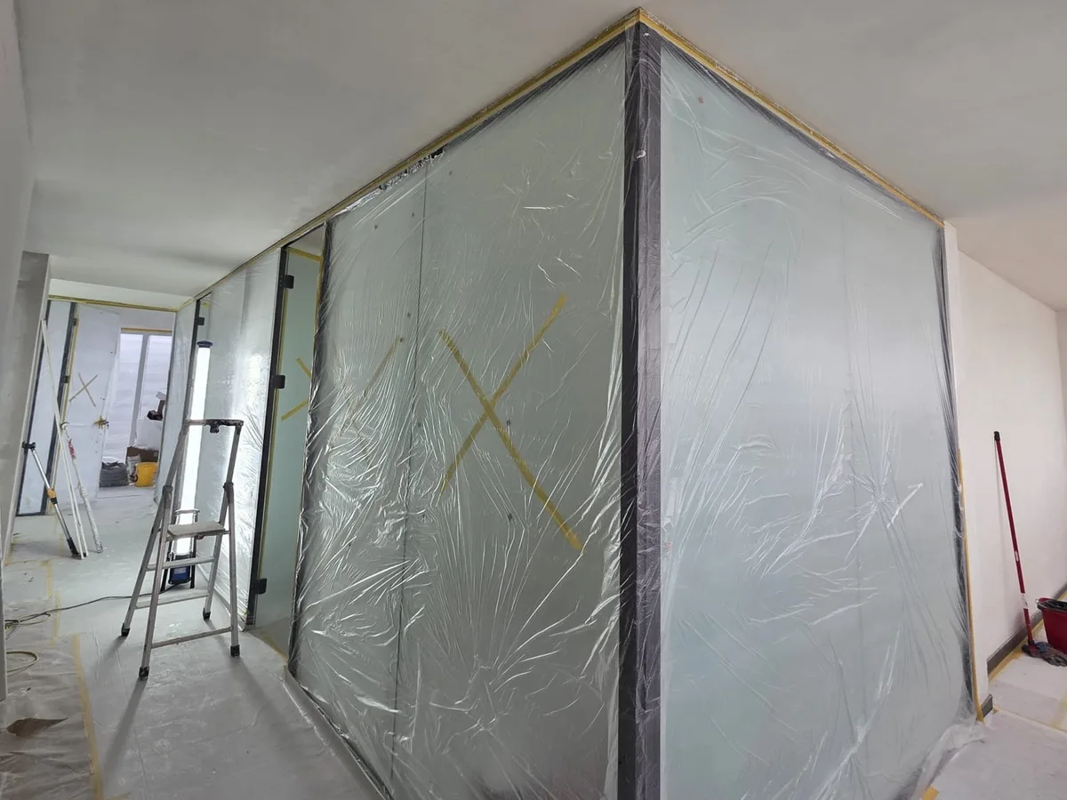 Cloisons vitrées protégées par des bâches pendant les travaux, couloir encore sous protection de sol