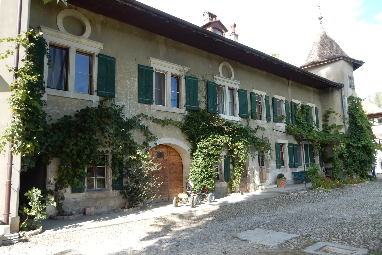 Maison ancienne en pierre à Nyon, façade côté lac couverte de vigne