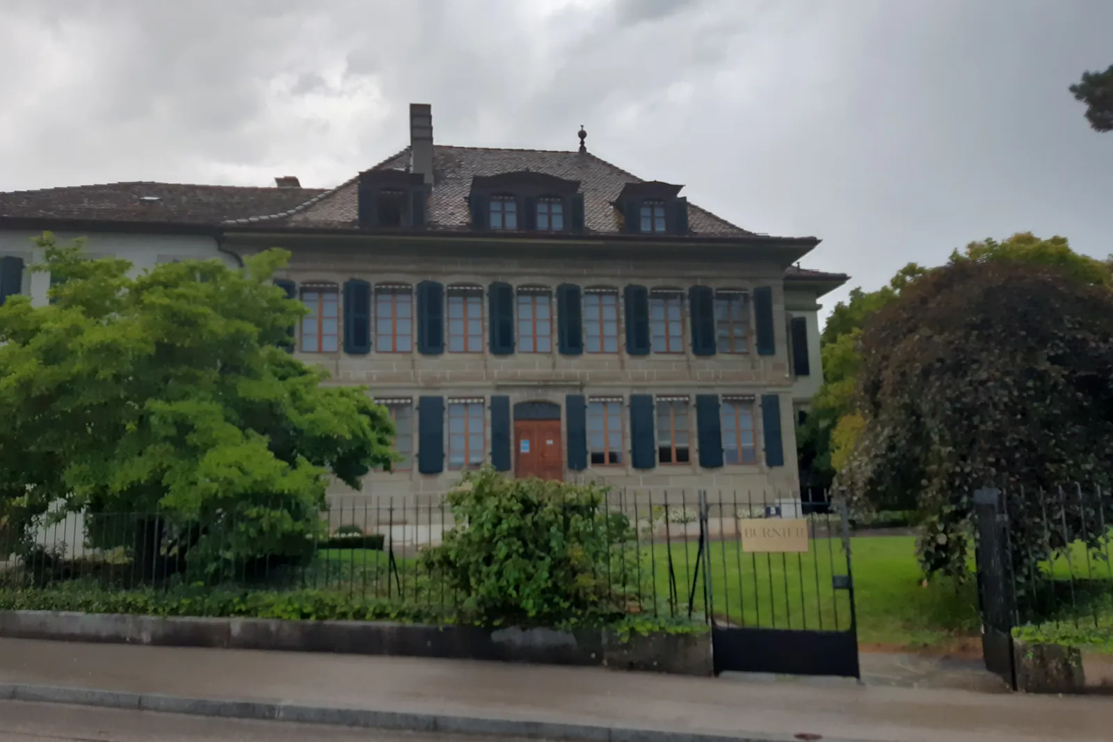 Façade d'une maison de maître à Nyon, derrière un jardin clos