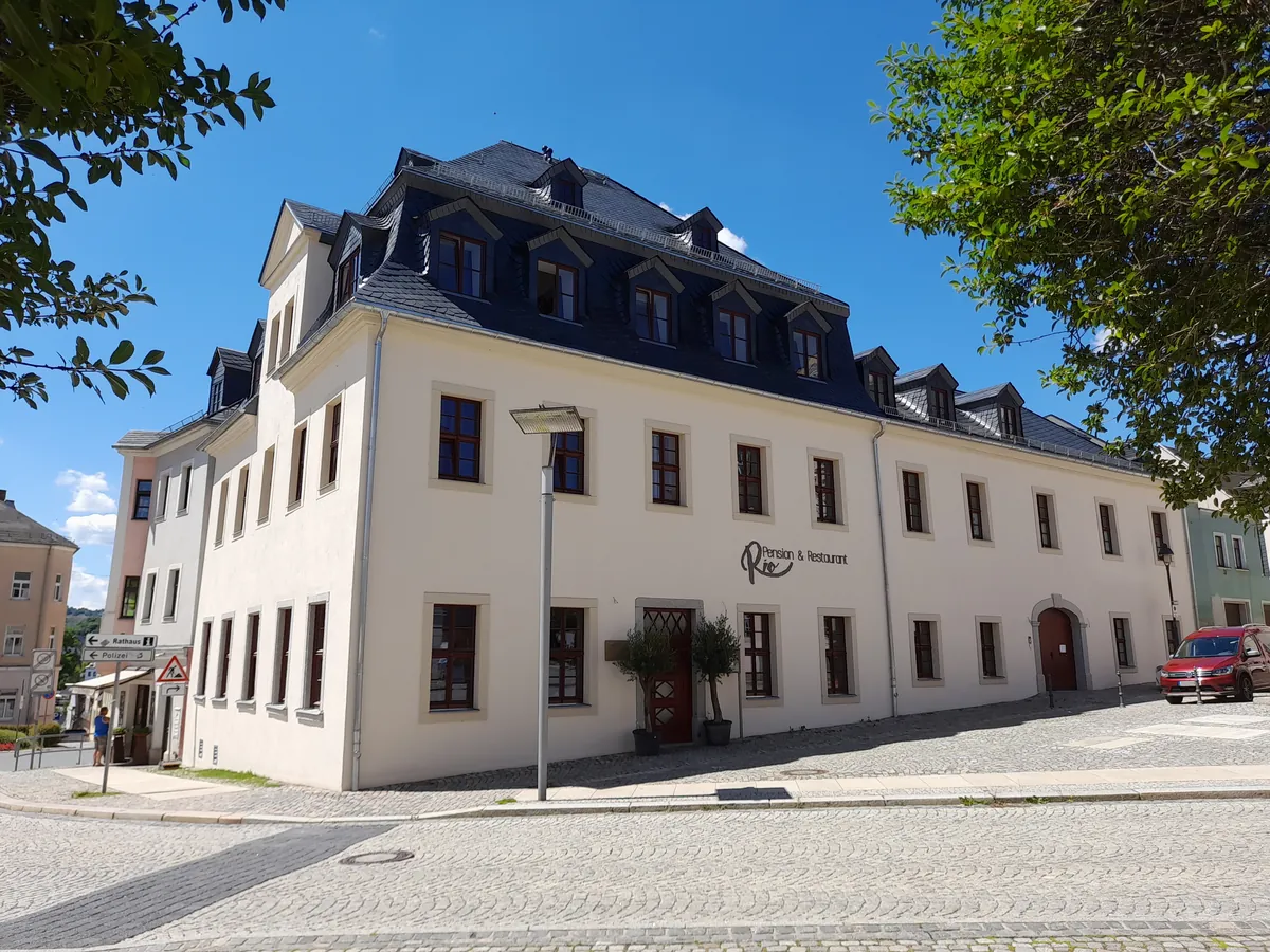 La même maison après rénovation, façade claire, toiture d'ardoise refaite et fenêtres neuves