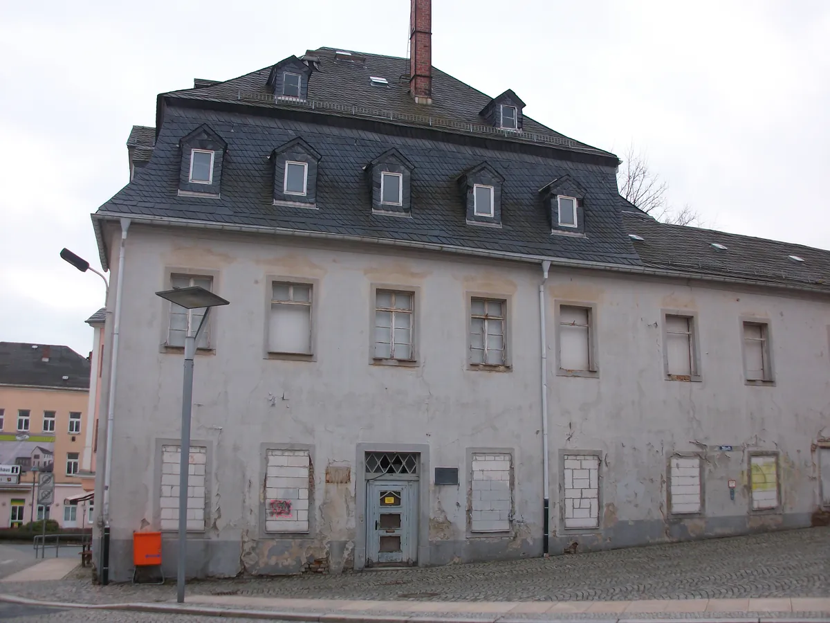 Maison de ville à toit mansardé, façade grise décrépie et fenêtres condamnées, avant rénovation