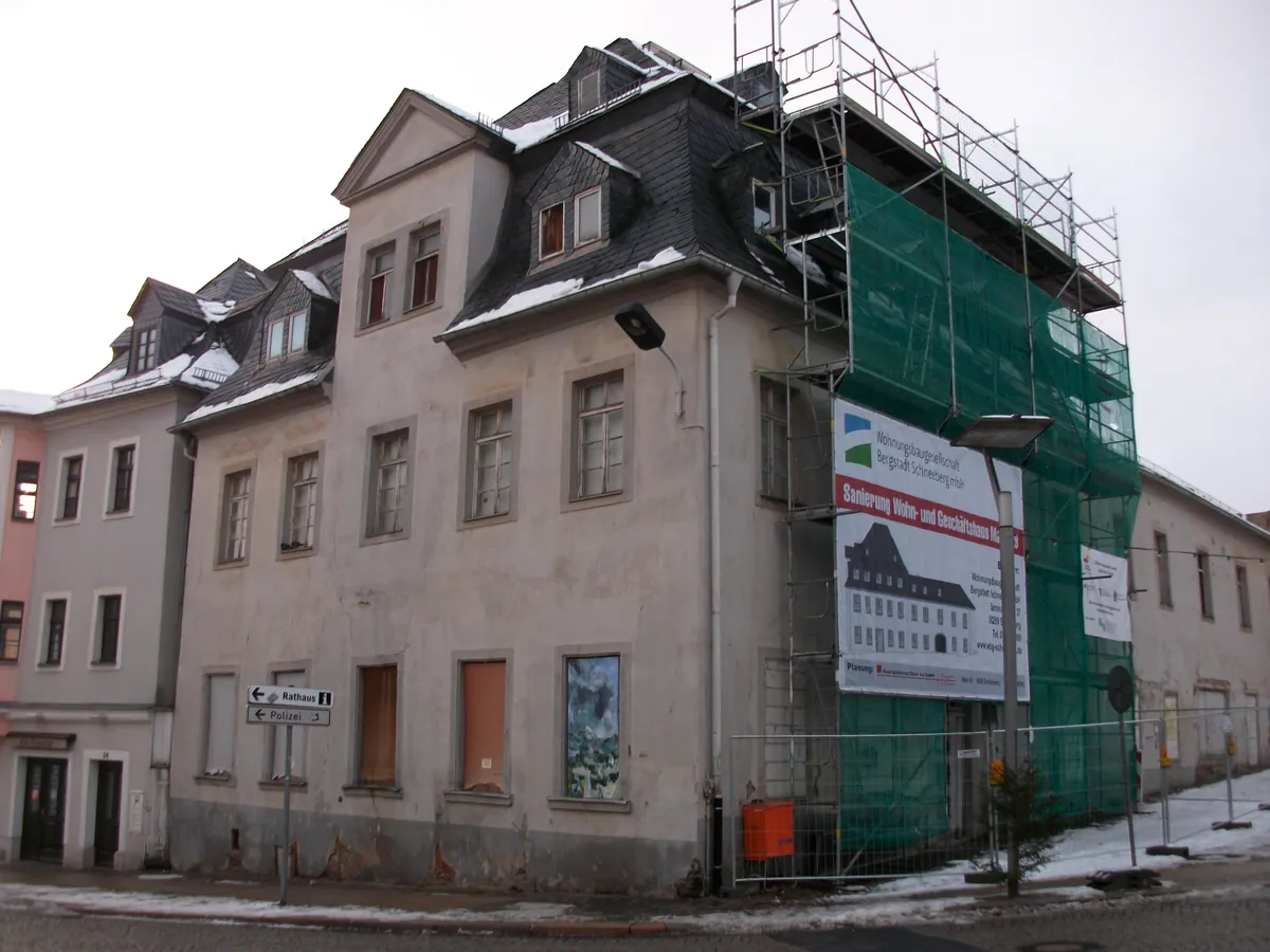 La même maison pendant les travaux, une façade sous échafaudage et bâche verte